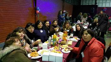 La imagen puede contener: 8 personas, personas sonriendo, personas sentadas, tabla, comida e interior